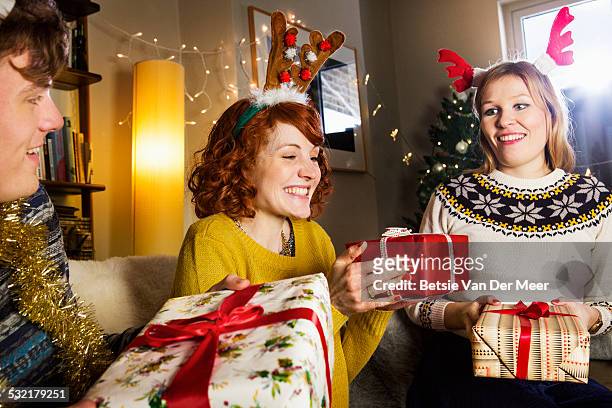 friends giving presents at christmas. - christmas present stock pictures, royalty-free photos & images