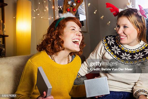 woman is pleased when opening christmas present. - christmas togetherness stock pictures, royalty-free photos & images