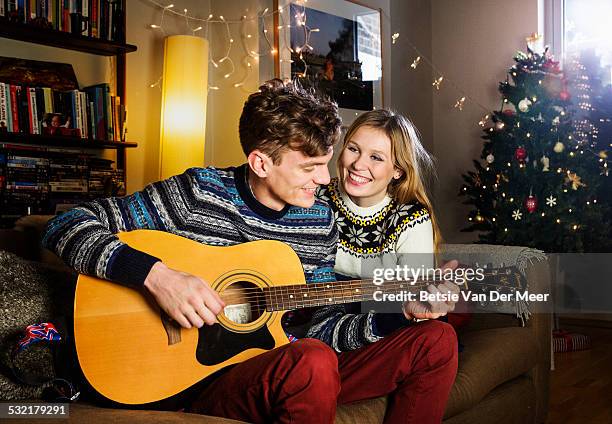 man serenades girlsfriend with guitar at christmas - een serenaden brengen stockfoto's en -beelden