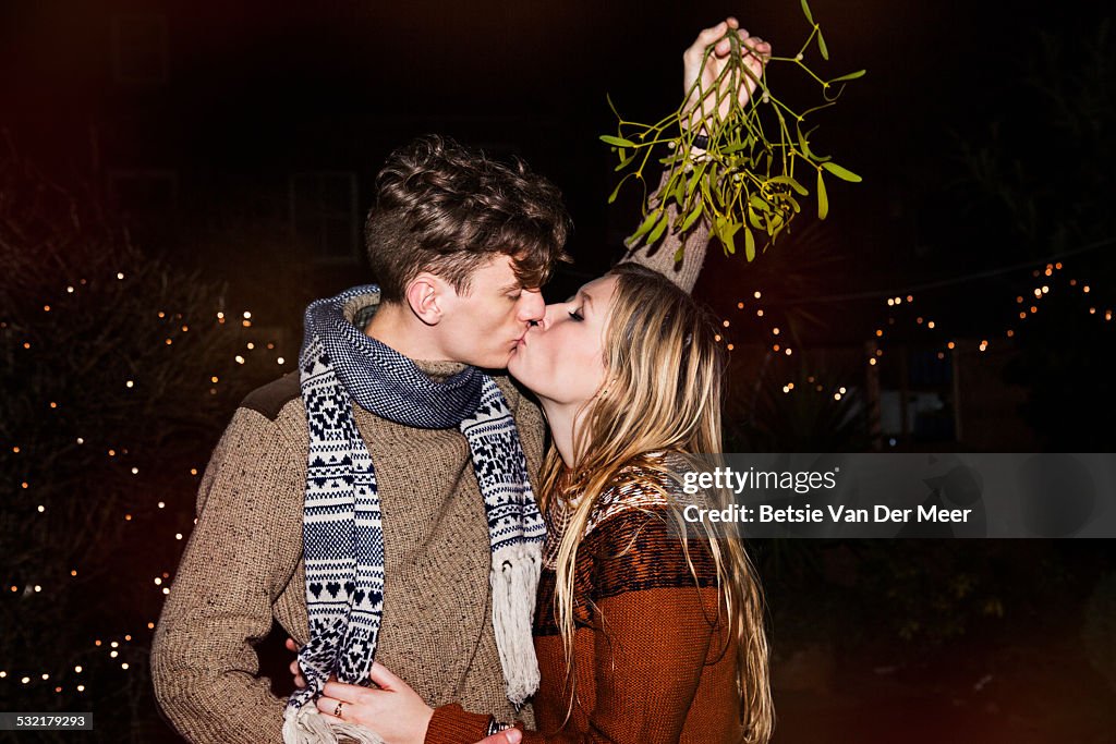Couple kissing outdoors under mistletoe