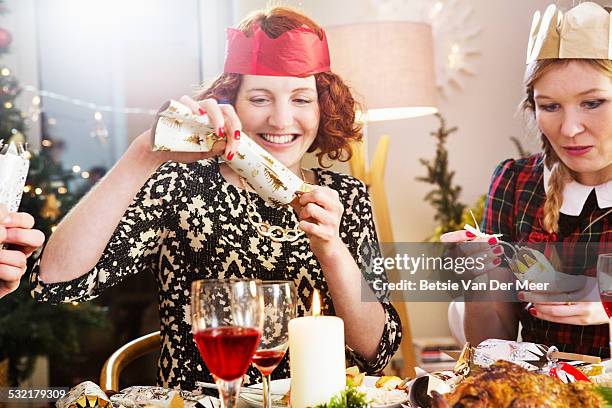 friends opening crackers at the christmas dinner. - smällkaramell bildbanksfoton och bilder