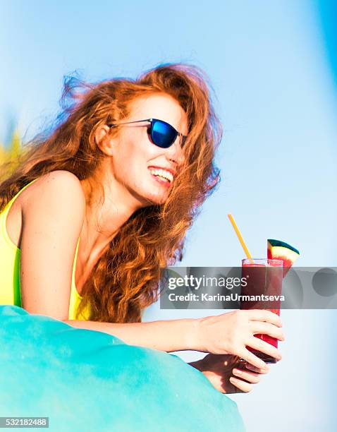 tropical red cocktail in hand of a young woman - holding sunglasses stockfoto's en -beelden