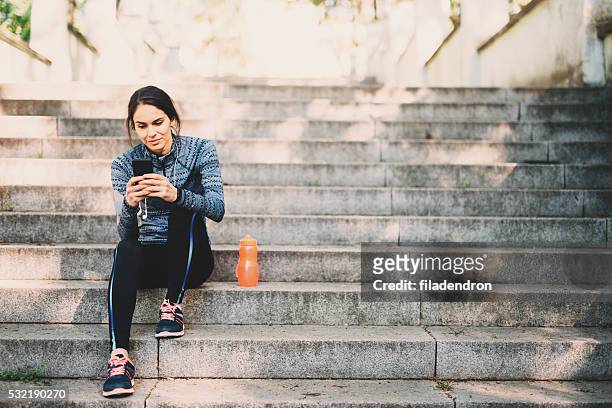 giovane donna a riposo dopo il jogging nel parco - net sports equipment foto e immagini stock