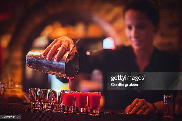 junge weibliche barkeeper gießen cocktails in der cocktail-bar - shot glass stock-fotos und bilder