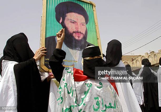 Iraqi women carry the picture of Shiite Muslim cleric Mahmoud al-Hassani during a demonstration outside the heavily guarded Iraqi authority building...