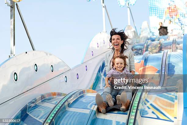 mother and her son on a slide at the carnival - kirmes fahrgeschäft stock-fotos und bilder