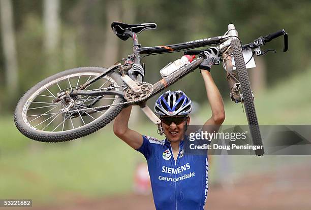 Christoph Sauser of Switzerland lifts his bike overhead in victory as he crosses the finish line during the Men's Cross Country Race at the UCI...