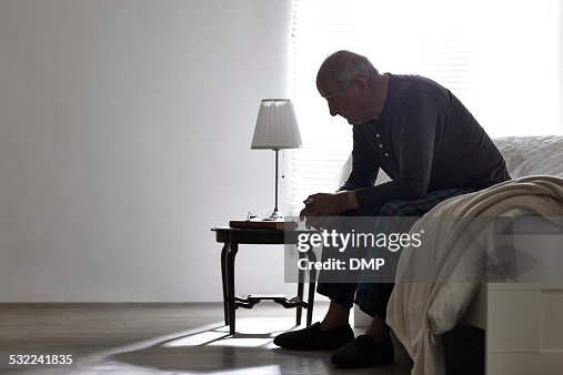 Idosos homem sentado na cama, olhando graves Idosos homem sentado na cama, olhando graves