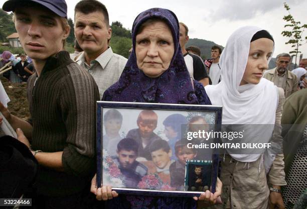 Bosnian Muslim woman carries a picture of children, victums of the 1995 Srebrenica massacre in the village of Potocari, 11 July 2005. The remains of...