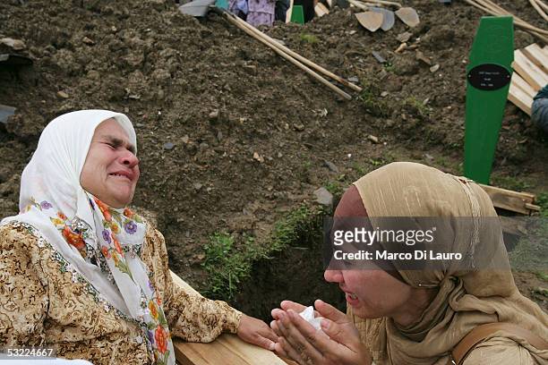 Relatives of the Srebrenica massacre victims cry in front of an empty grave as they attend the funeral of their family members at the Srebrenica...