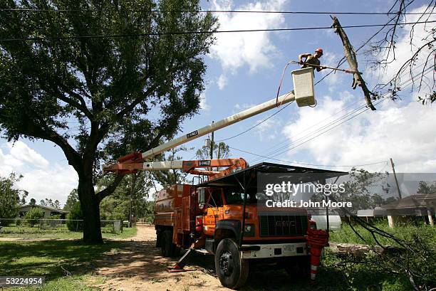 Jimmy Kimmons, an electrical worker for Gulf Power, cuts down broken tree limbs entangled in power lines July 11, 2005 in Pensacola, Florida. State...