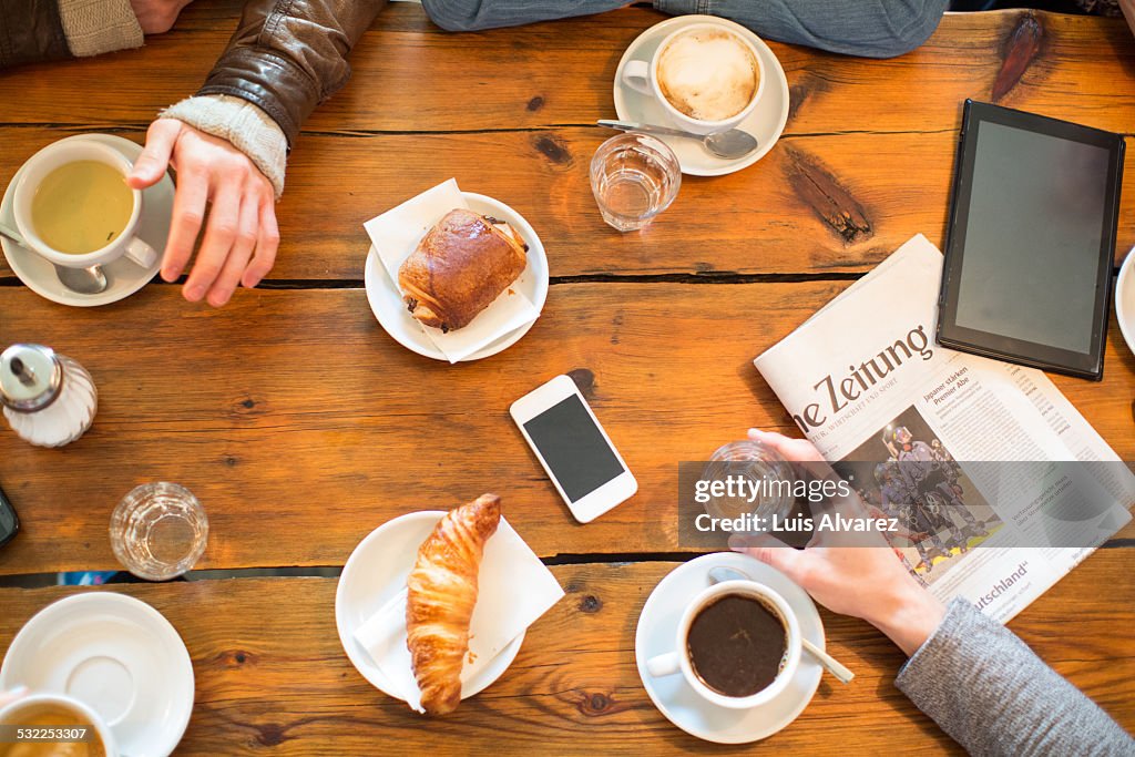 Friends having coffee and snacks at table