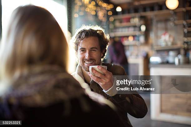 man having coffee while looking at woman in cafe - cafe fotografías e imágenes de stock
