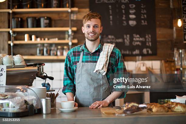 happy barista standing at cafe counter - barista foto e immagini stock