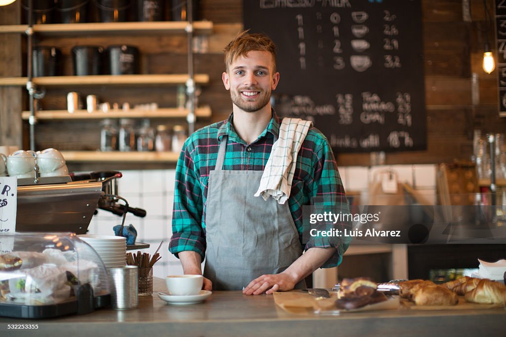 Happy barista standing at cafe counter