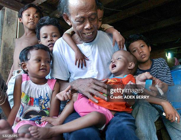 Junaidi holds his youngest son Rahmatullah suffering from malnutrition, with his other children in Jakarta, 05 Jully 2005. With its Gucci-filled...