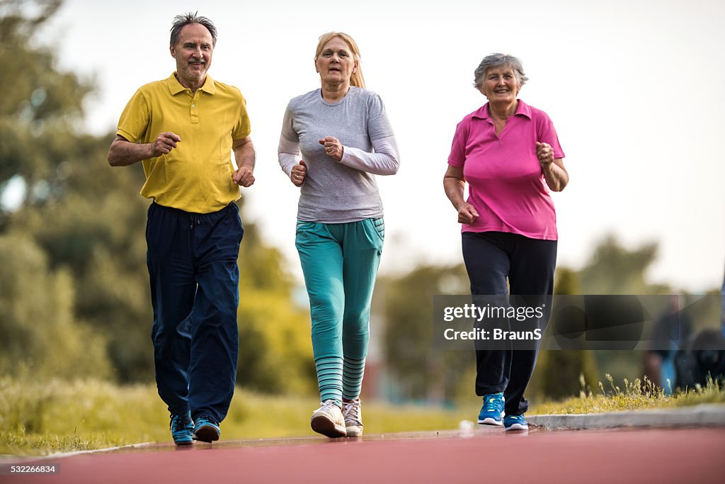 Group of old people jogging on running track outdoors.