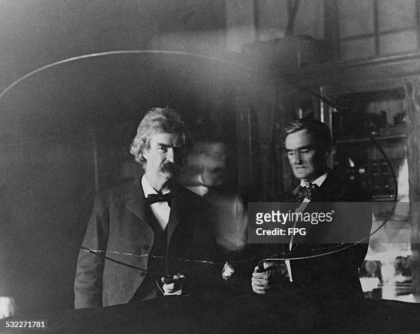 Serbian-American inventor and engineer Nikola Tesla performs an electrical experiment for writer Samuel Langhorne Clemens, aka Mark Twain and actor...
