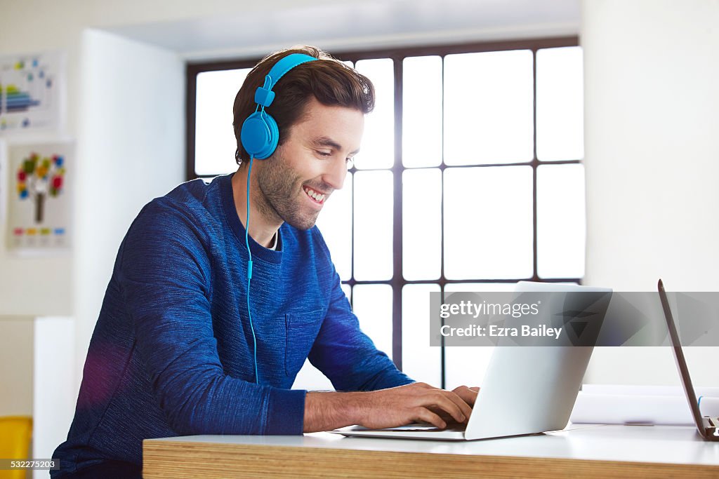 Man working in an open office with headphones on.