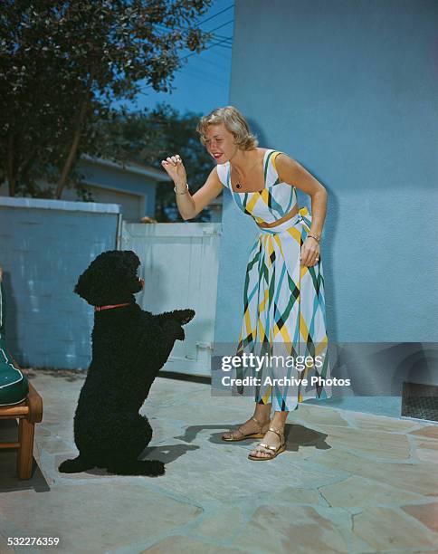 American actress and singer Doris Day playing with a dog, circa 1950.