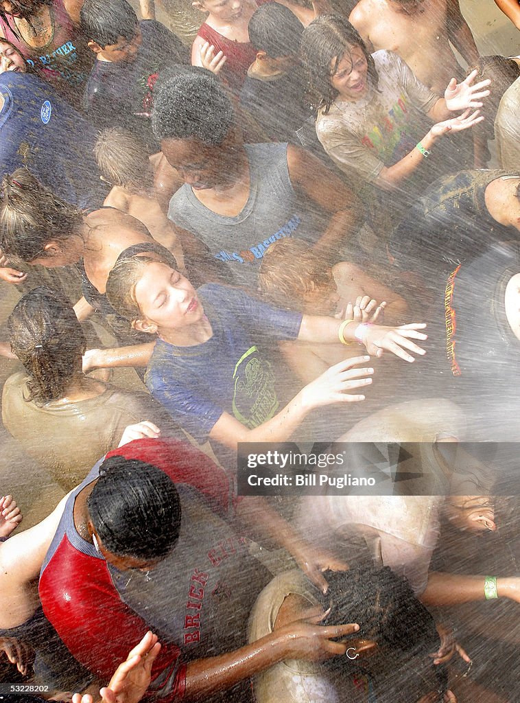 People get mud hosed off of them by a hose from a fire truck during ...