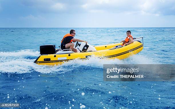 father and son on an inflatable boat - speedboat stock pictures, royalty-free photos & images