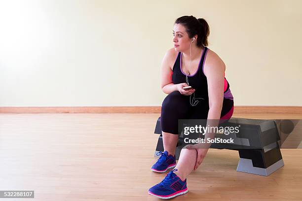 young woman stretching wearing earphones - fat legs stock pictures, royalty-free photos & images