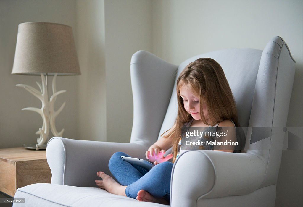 Girl sitting on a chair with a tablet