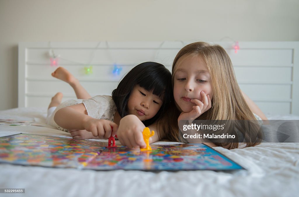 Girls playing a table game in a bed