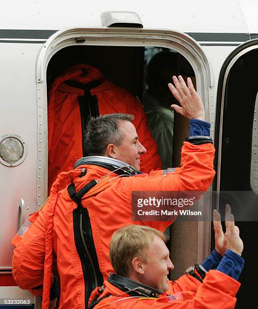 Space Shuttle Discovery astronauts Stephen Robinson and Andrew Thomas wave to the news media as they walk from the crew area and enter the astronaut...