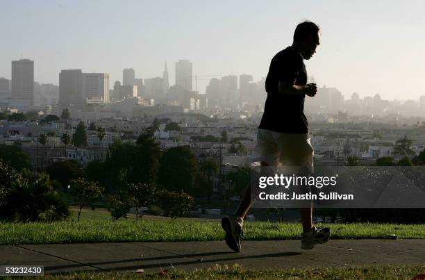 With the San Francisco skline in the background, a jogger runs through Dolores Park July 13, 2005 in San Francisco. Runner's World Magazine has just...