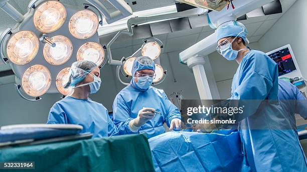 los cirujanos en funcionamiento de teatro - operating room fotografías e imágenes de stock