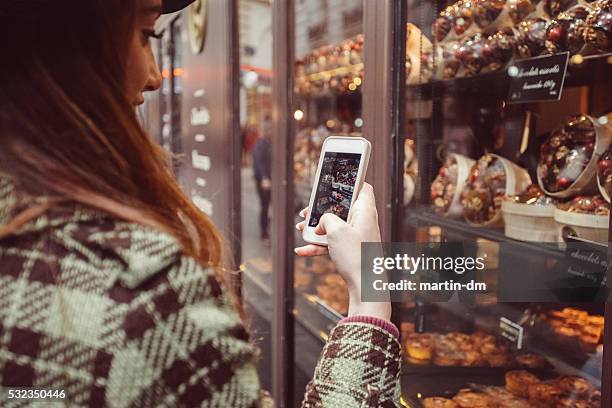 donna fotografare il negozio di dolciumi finestra - boulangerie paris foto e immagini stock