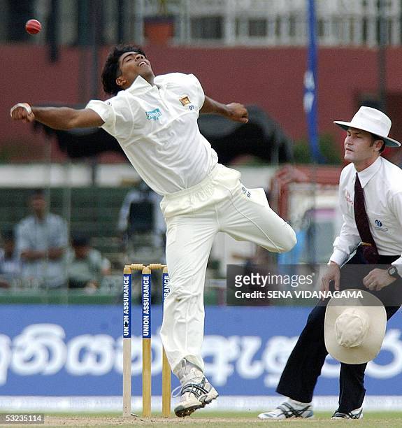 Sri Lankan cricketer Lasith Malinga is watched by umpire Simon Taufel as he attempst to hold onto a caught and bowled chance during the second day of...