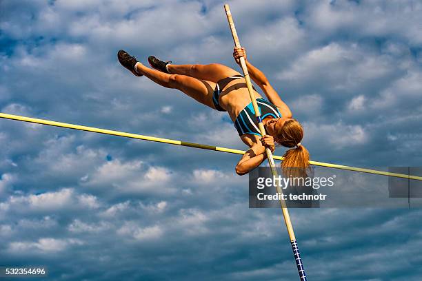young women jumping over the lath against cloudy sky - stavhopp bildbanksfoton och bilder