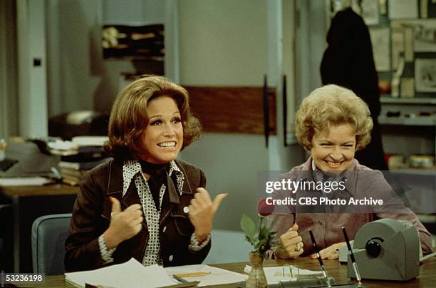 American actress Mary Tyler Moore gives a 'thumbs up' sign as she sits at her desk with Betty White in a scene from 'The Mary Tyler Moore Show' , Los...