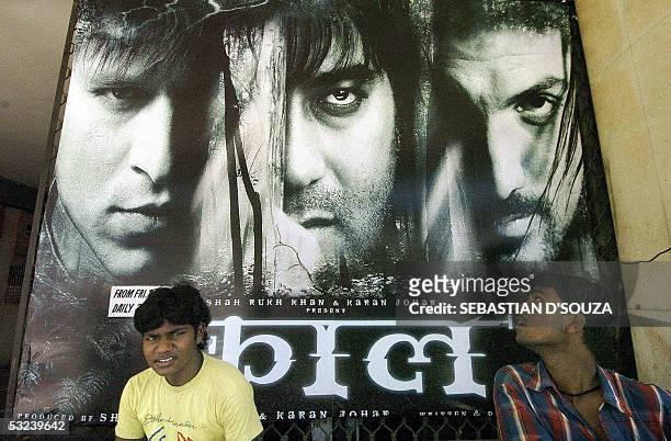 In this file photograph dated 29 April 2005, Indian cinema goers sit in front of a billboard advertising the film 'Kaal' outside a cinema hall in...