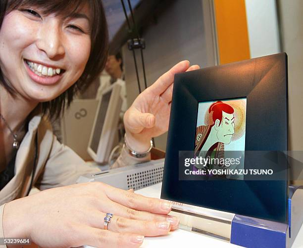 Japan's computer giant Fujitsu employee Sachiko Iino displays a prototype model of an electronic paper display, 3.8-inch QVGA 512-color LCD, enabling...