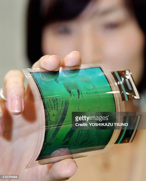 Japan's computer giant Fujitsu employee Sachiko Iino displays a prototype model of an electronic paper display, film-based flexible mono-color LCD,...