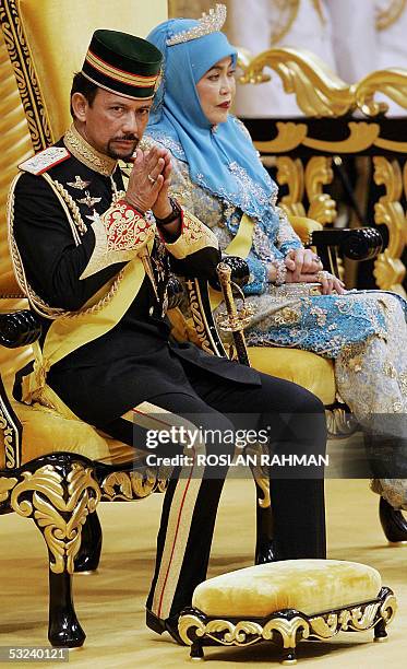 Bruneian Sultan Hassanal Bolkiah greets while Queen Saleha looks on during a ceremony for his birthday celebration at his palace in Bandar Seri...