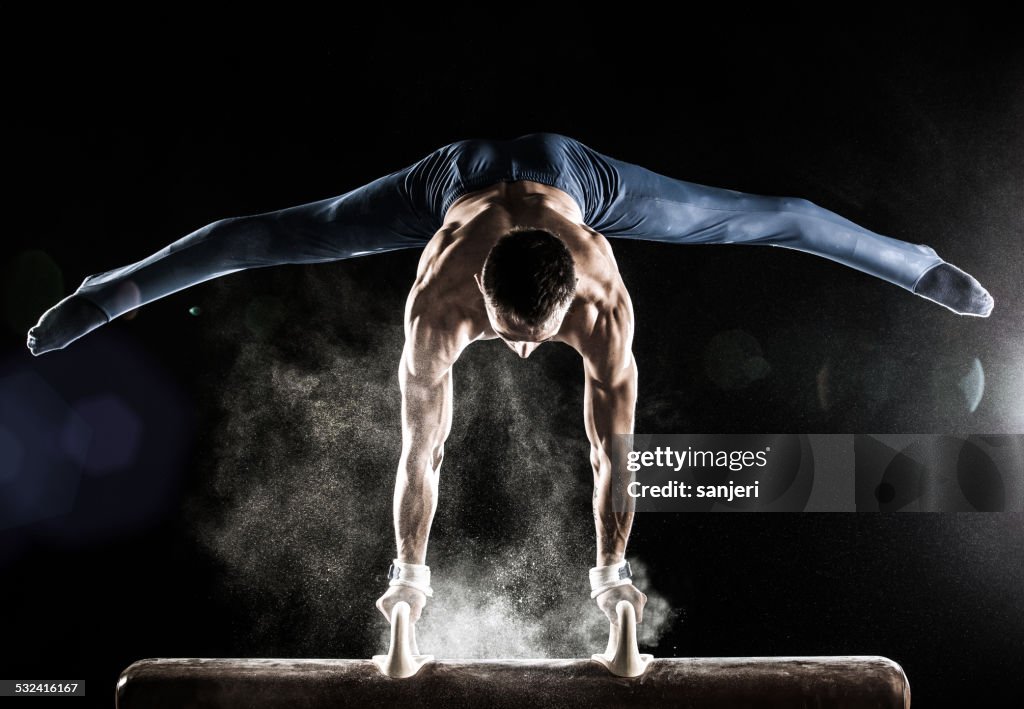 Male Gymnast doing handstand on Pommel Horse