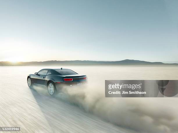 black sports car driving on dry lake bed - car speeding stock-fotos und bilder