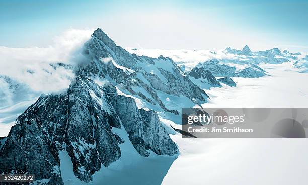 aerial shot of mountains covered with snow - glacier stock-fotos und bilder