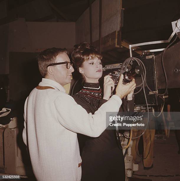 English actor and comedian Peter Sellers demonstrates the settings on a single-lens reflex camera to American singer Fran Jeffries on the set of the...