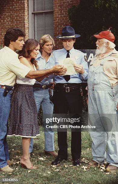 Members of the Duke clan make worried faces as they look at a letter held Deputy Enos Strate in a scene from the television series 'The Dukes of...