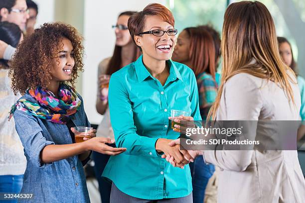 student introducing parent to teacher during meet and greet party - party board meets stock pictures, royalty-free photos & images