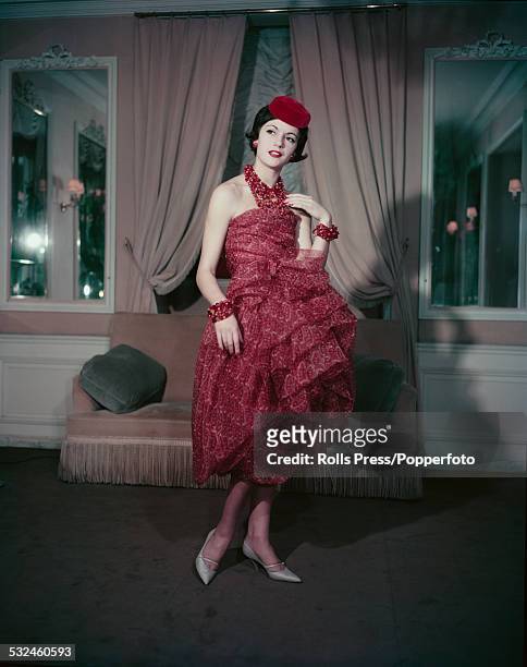 Fifties Fashion - A young female model wears a short evening dress fashioned in chiffon with a rusted paisley pattern, many stranded necklace with...