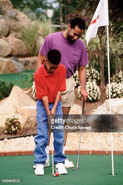 father and son playing miniature golf - miniature golf fotografías e imágenes de stock