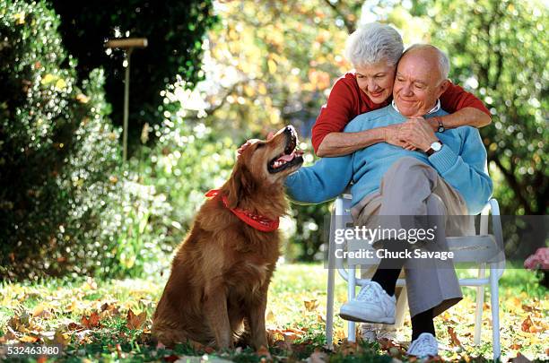 affectionate couple petting the dog - savage dog stock pictures, royalty-free photos & images