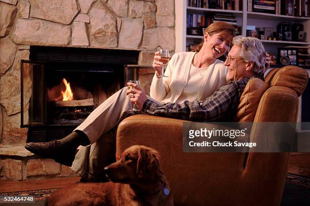couple drinking wine in front of fireplace - savage dog fotografías e imágenes de stock